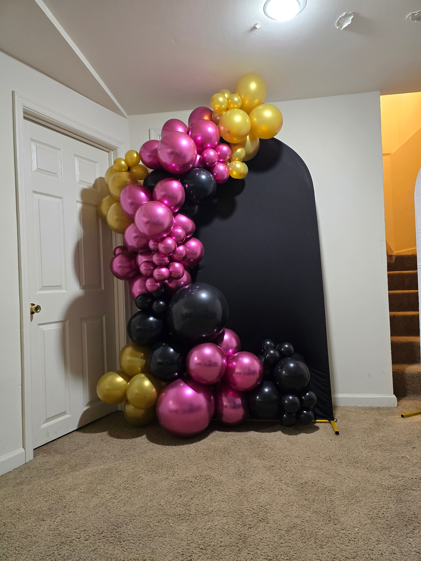 Magenta, gold and black organic balloon garland on a black arched backdrop by Simone's Creations DMV