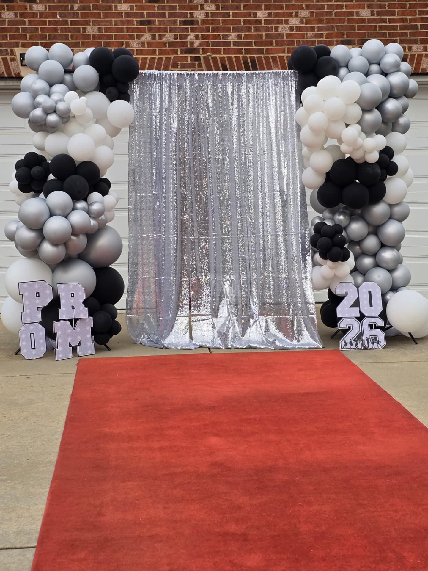Prom send-off balloon arch with red carpet, silver shimmer backdrop and 2026 marquee letters by Simone's Creations DMV